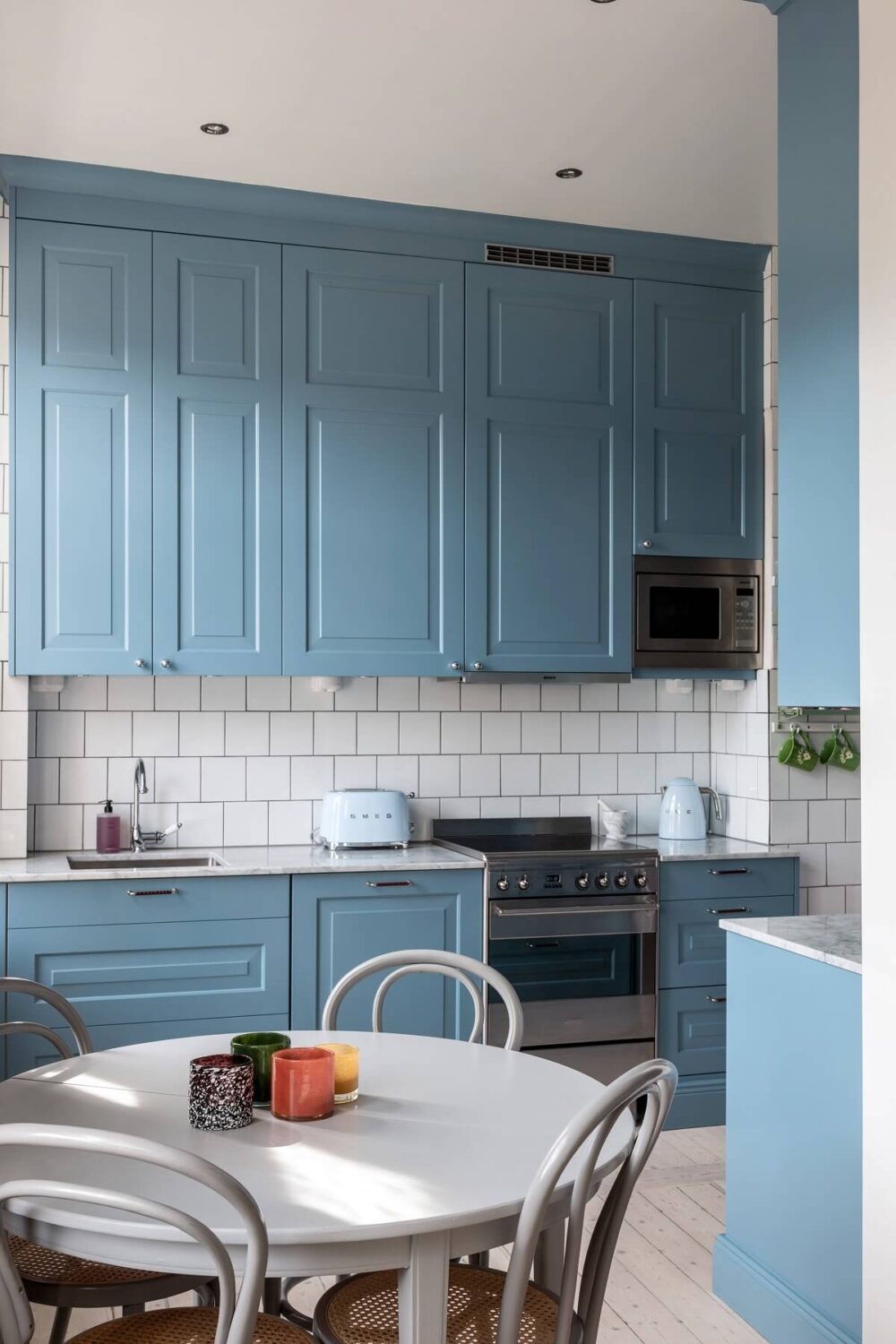A Nordic Home with Blue Sitting Room and Kitchen 11 blue-kitchen-cabinets-round-dining-table-nordroom