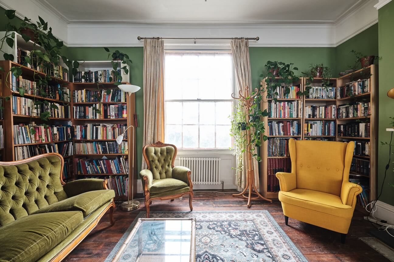 A Colorful Eclectic Home in England 6 green-sitting-room-bookshelves-yellow-armchair-nordroom