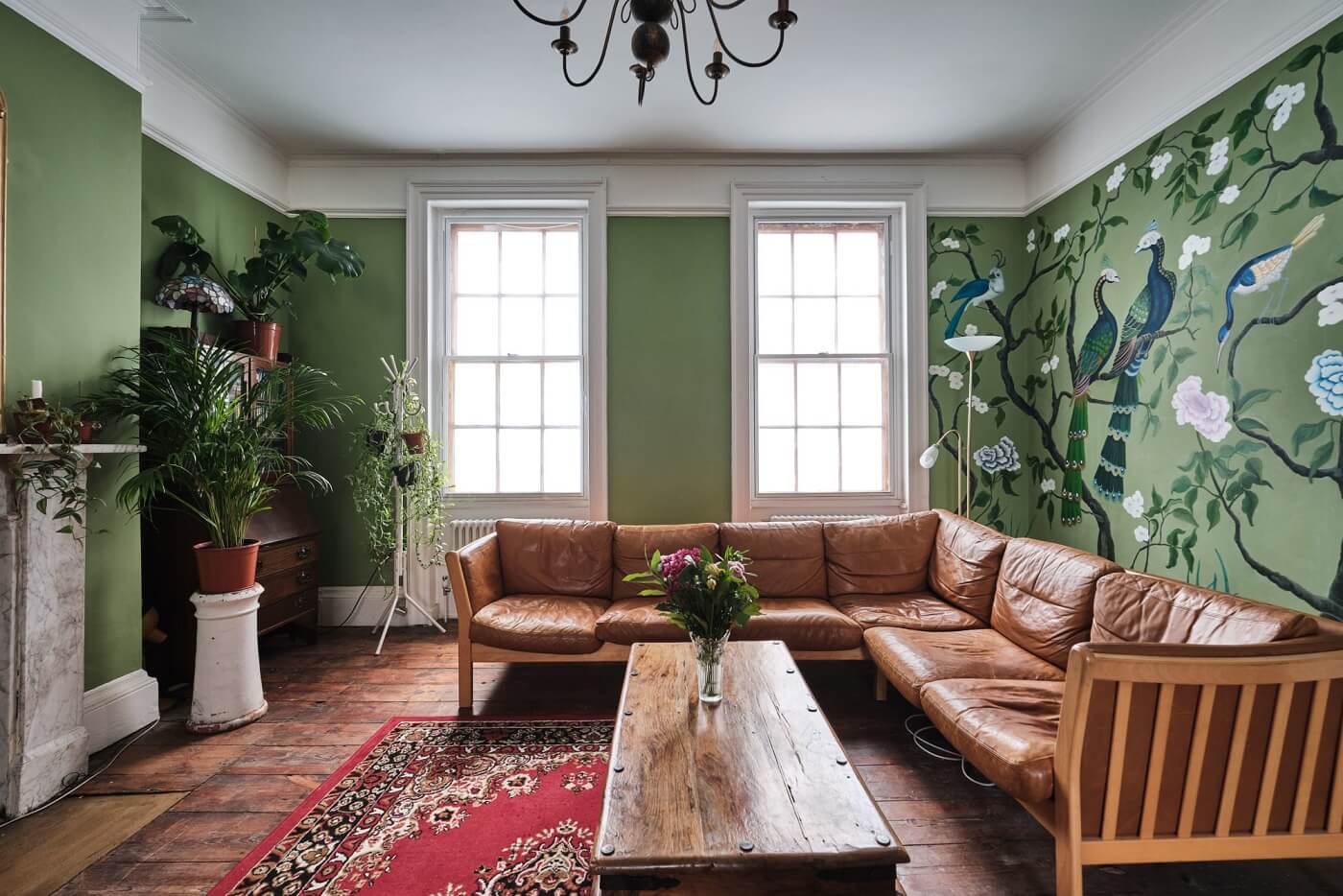 A Colorful Eclectic Home in England 11 green-sitting-room-tan-leather-sofa-green-mural-nordroom