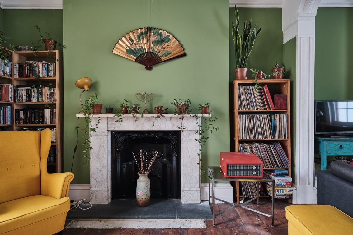 A Colorful Eclectic Home in England 8 green-sitting-room-yellow-armchair-fireplace-nordroom