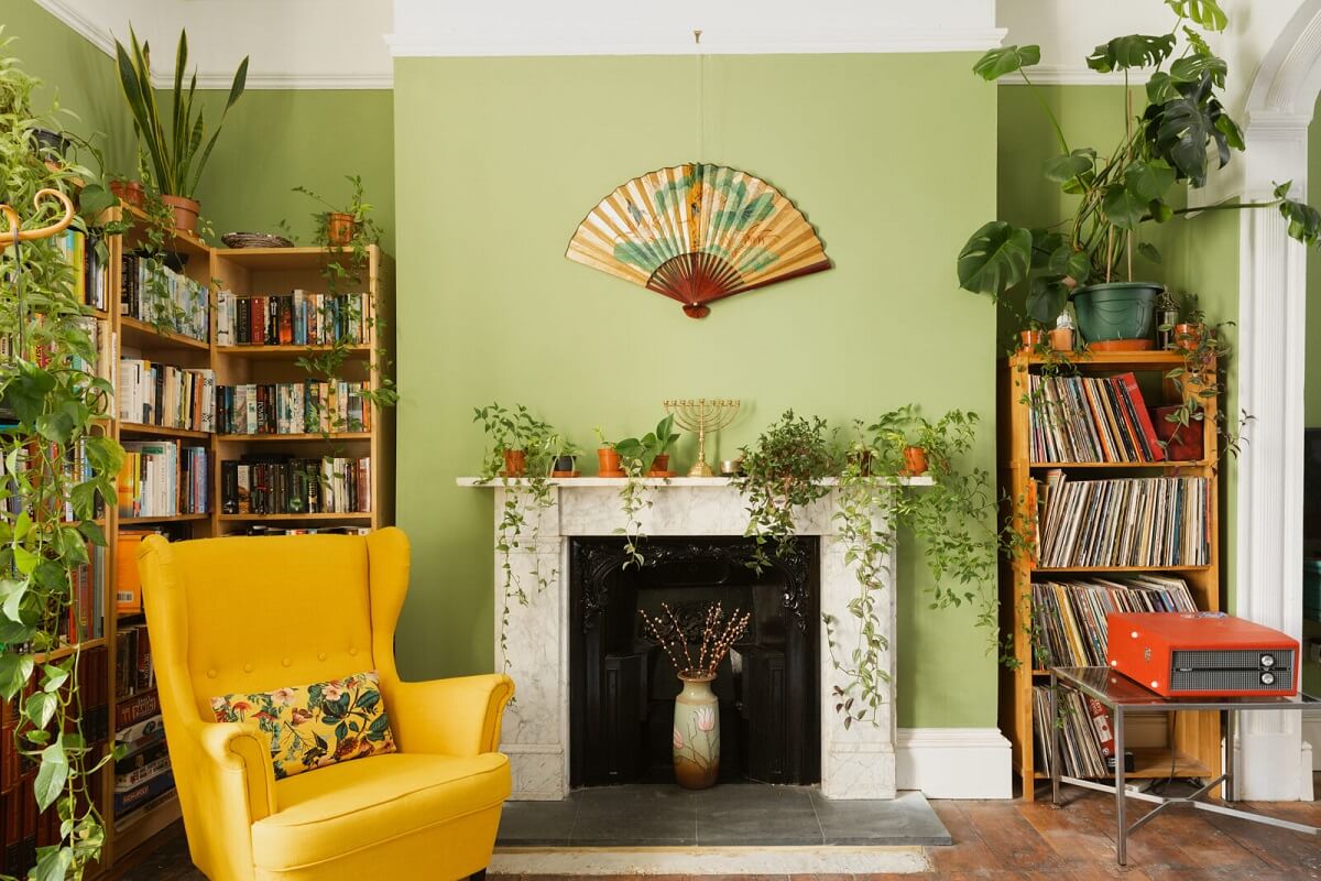 A Colorful Eclectic Home in England 4 living-room-green-walls-fireplace-yellow-armchair-bookcases-nordroom