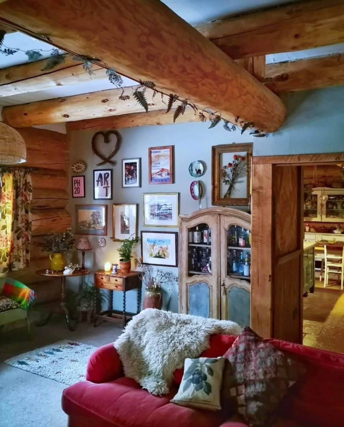 Imrich Lodge: A Cozy Self-Built Log House in the Scottish Highlands 2 living room pink sofa gallery wall exposed beams nordroom Imrich Lodge: A Cozy Self-Built Log House in the Scottish Highlands