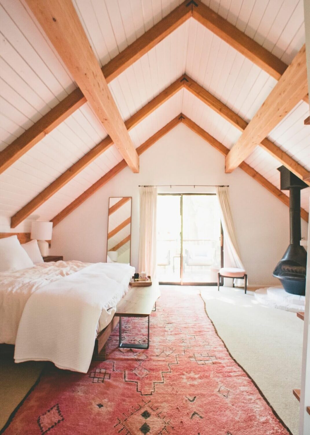 The Kitchy Cabin: A Lovely Airbnb Home in California 12 master-bedroom-sloped-ceiling-pink-rug-exposed-beams-nordroom