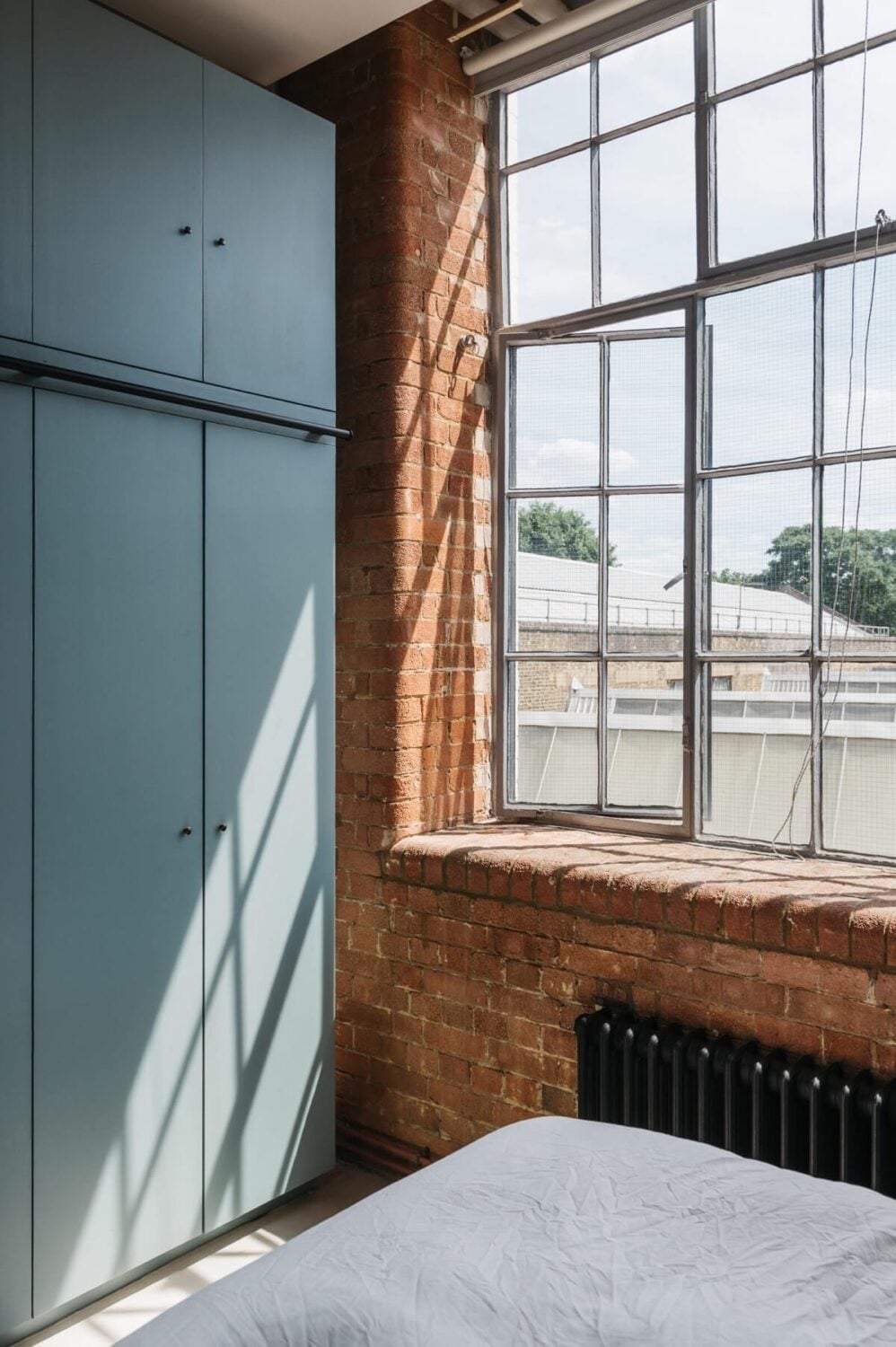 A Loft-Style Apartment with Brick Walls in London 16 bedroom-industrial-window-brick-wall-blue-wardrobes-nordroom