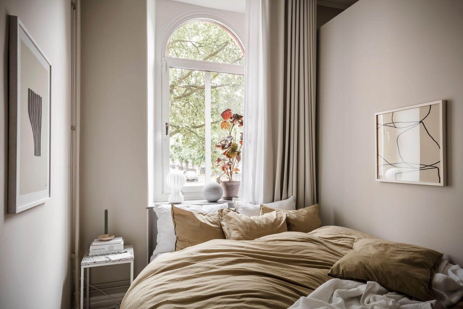 A Tiny and Stylish Nordic Apartment 17 small-sand-colored-bedroom-ochre-bedding-arched-window-nordroom