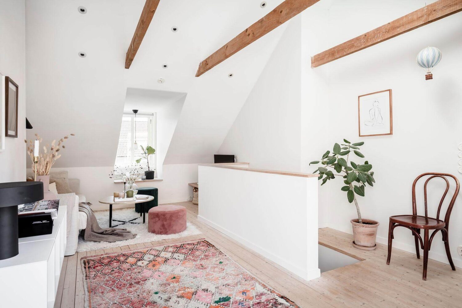 A Living Room with Pink Accents in a Light Attic Apartment 4 attic-floor-living-room-pink-rug-exposed-beams-nordroom