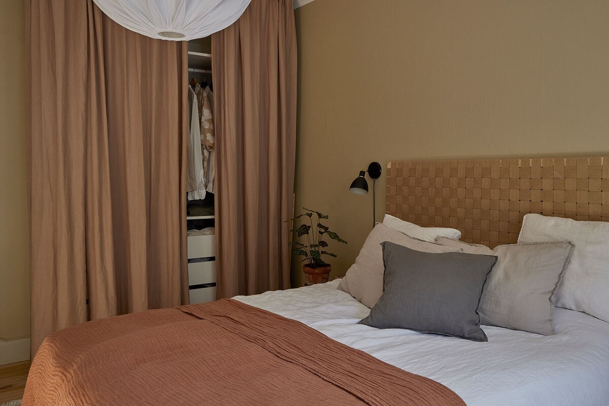 A Small Nordic Home Decorated in Warm Light Colors 13 bedroom-beige-green-wals-pink-bedspread-wardrobe-behind-curtains-nordroom
