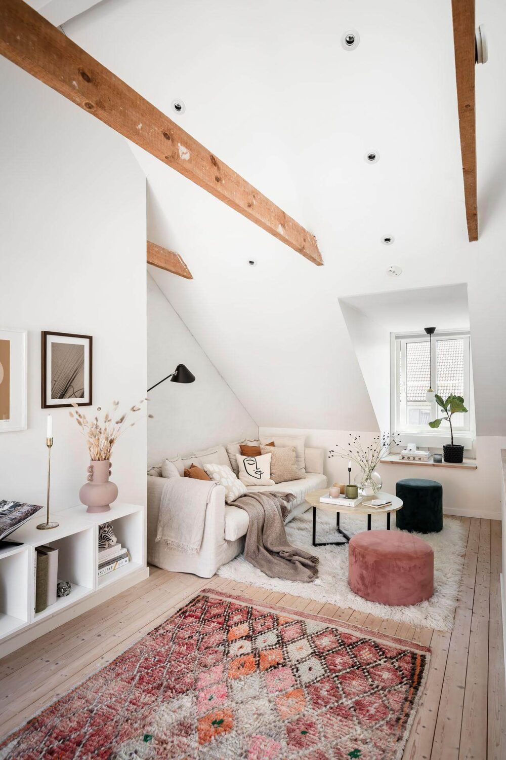A Living Room with Pink Accents in a Light Attic Apartment 1 bright-living-room-exposed-beams-pink-rug-scandinavian-design-nordroom