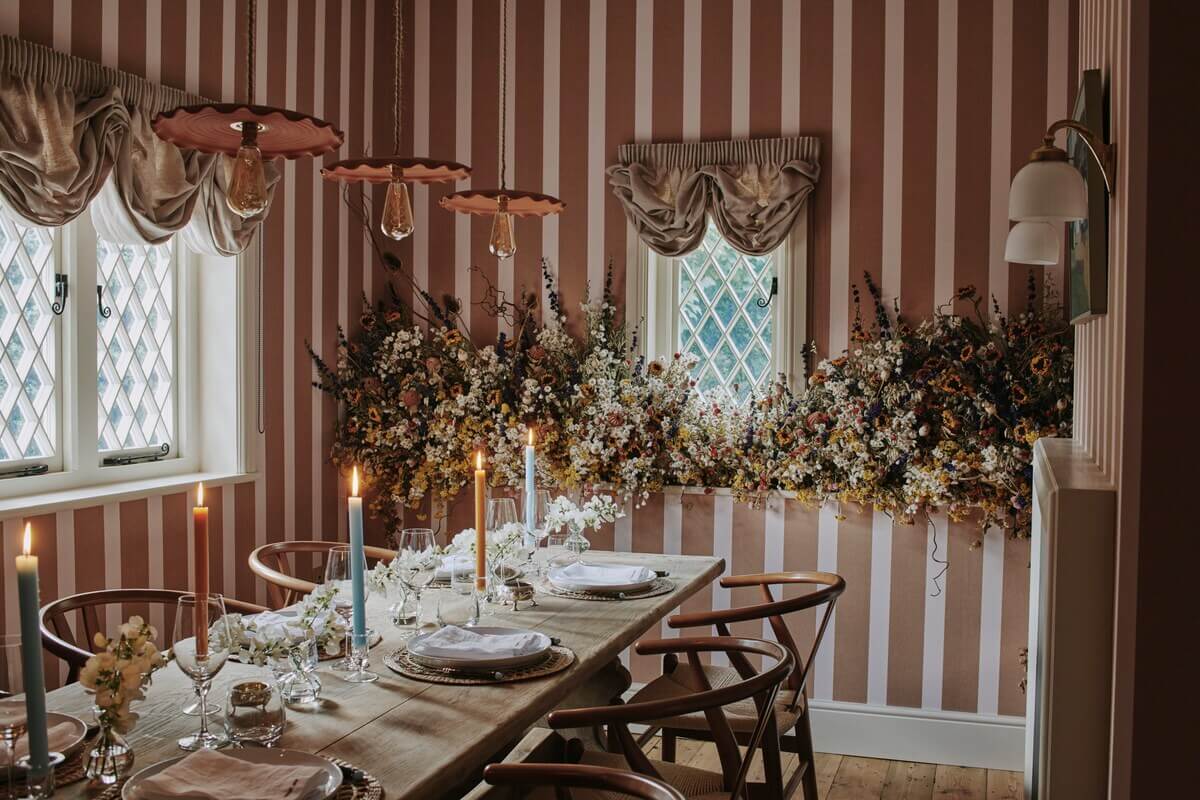 A Magical Pink Cottage in the English Countryside 2 cottage-dining-room-striped-earthy-red-wallpaper-rustic-dining-table-wishbone-chairs-nordroom