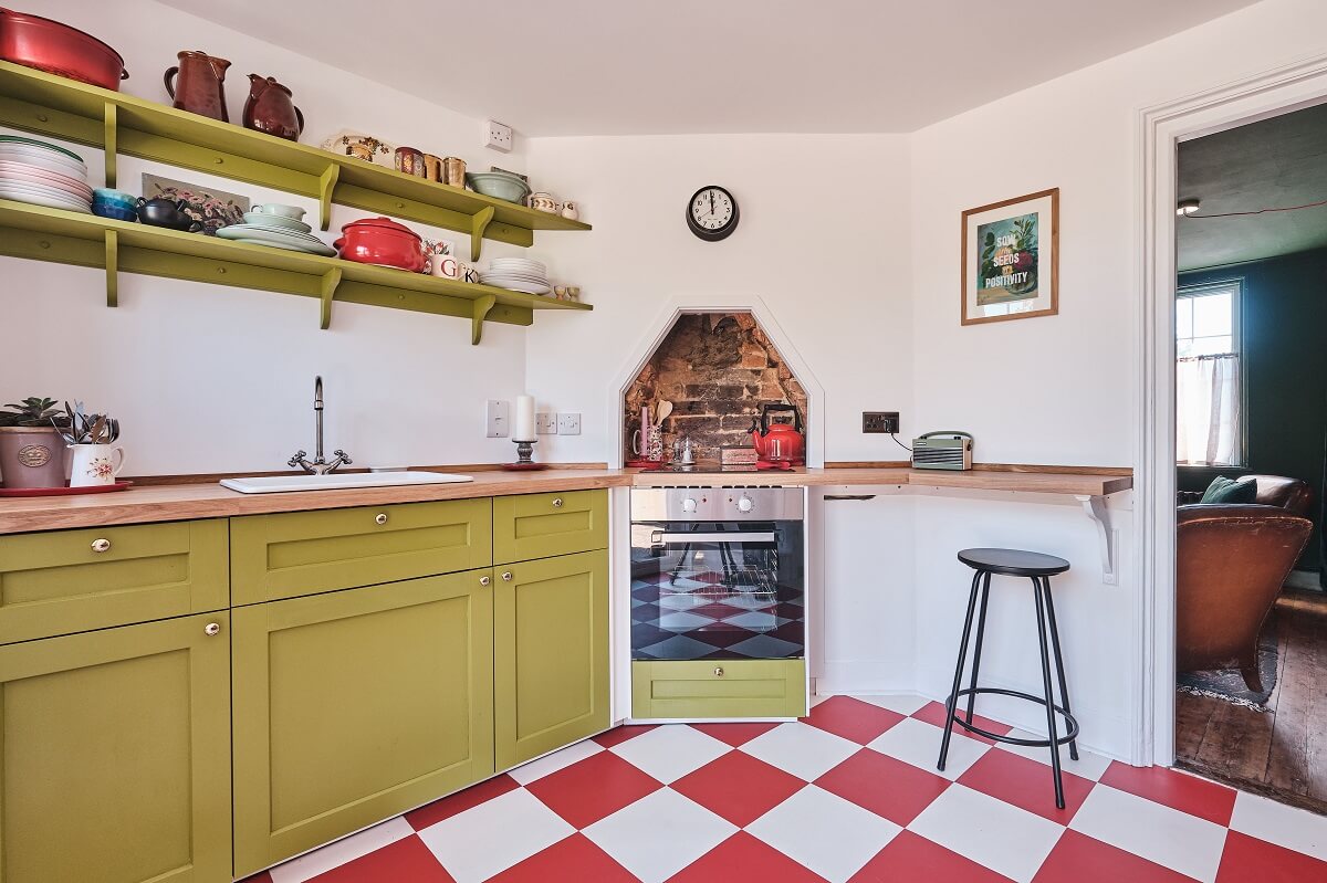 Bold Colors in a Charming English Cottage 8 green-kitchen-cabinets-shelves-red-white-checkerboard-floor-nordroom