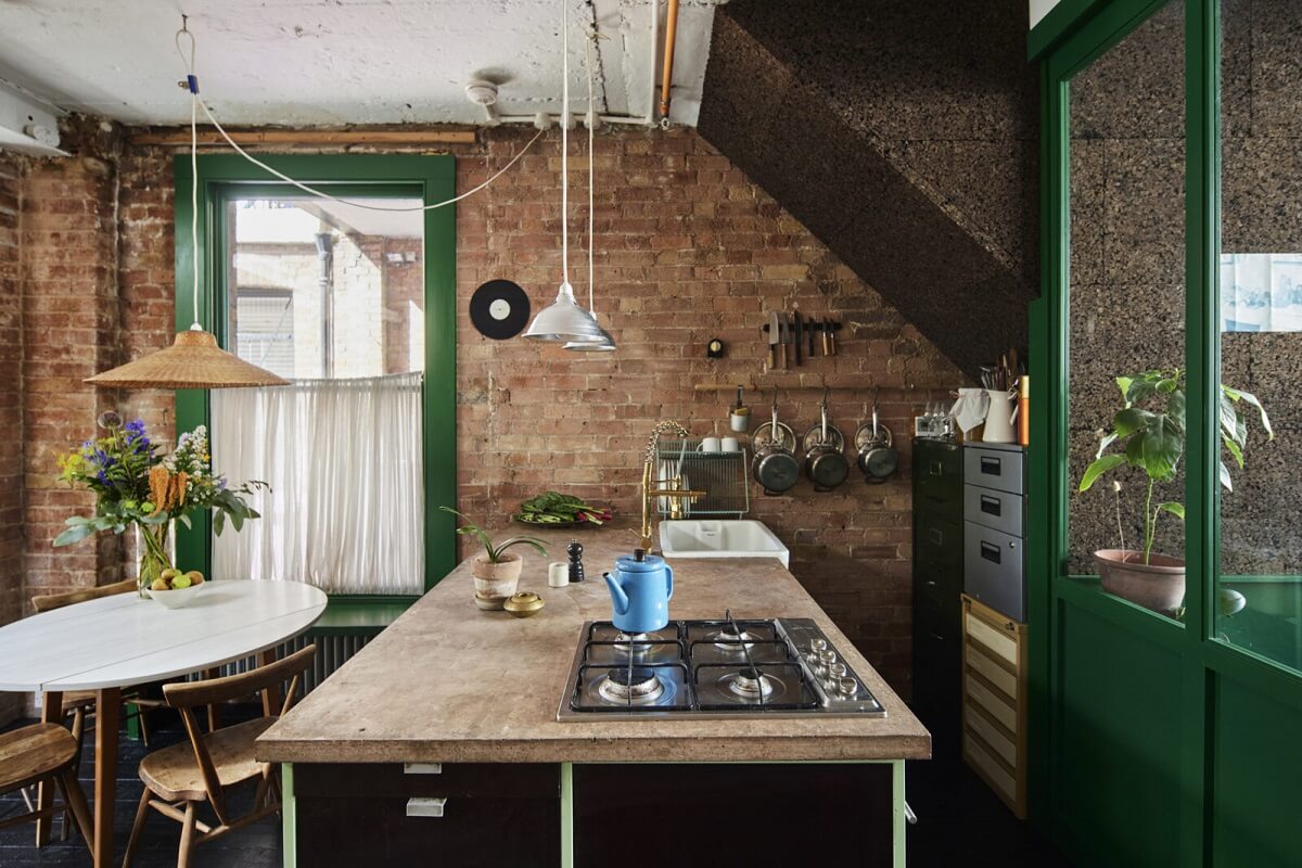 A Unique Home in a Former Furniture Workshop 6 kitchen-brick-wall-island-round-dining-table-green-window-trims-nordroom