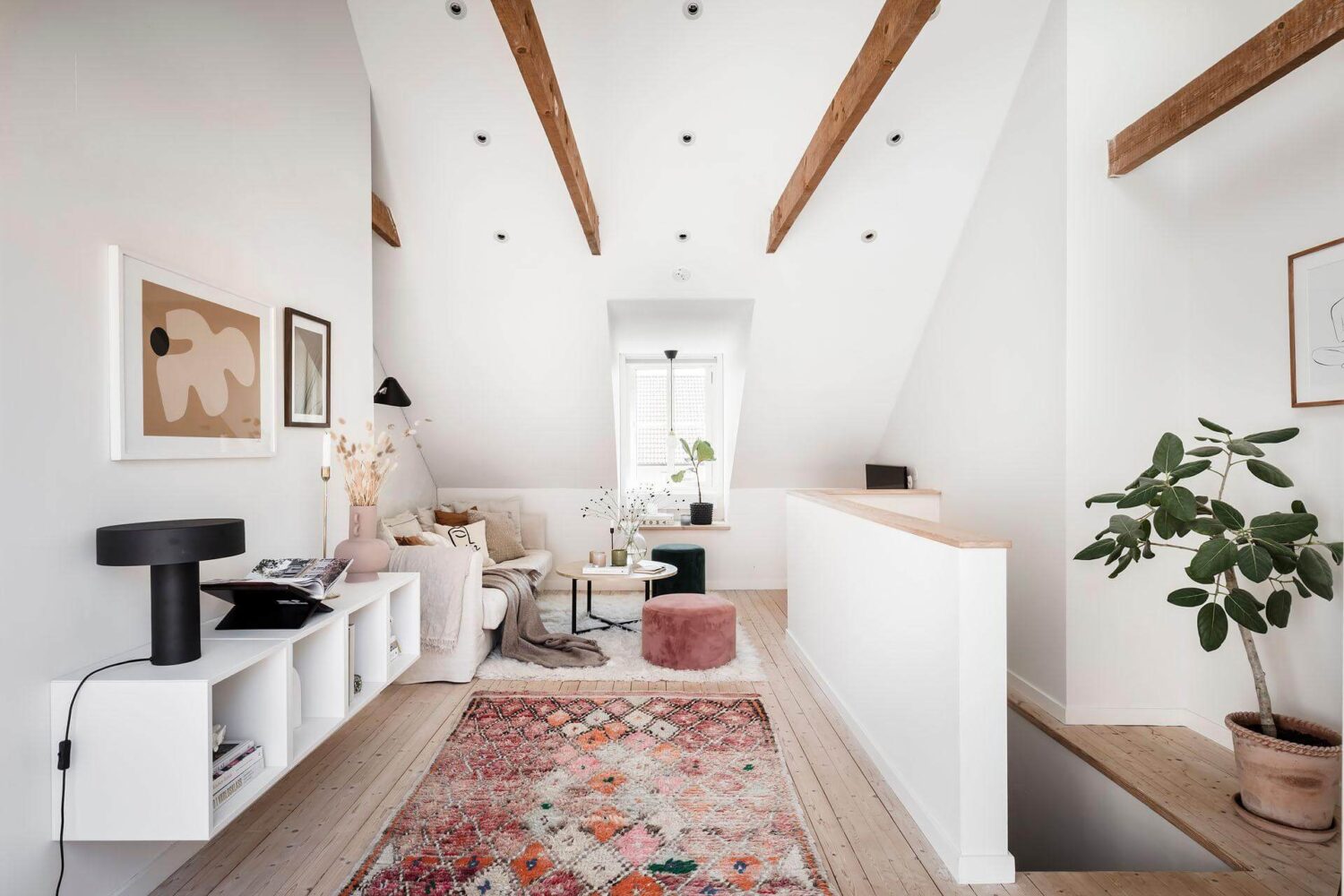 A Living Room with Pink Accents in a Light Attic Apartment 2 light-attic-living-room-exposed-beams-wall-mounted-cabinets-wooden-floor-nordroom