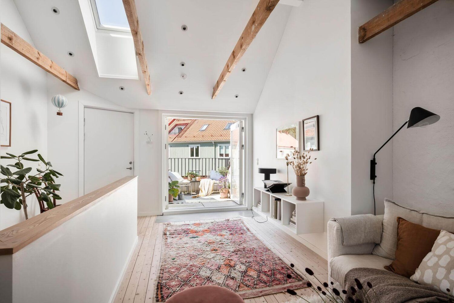 A Living Room with Pink Accents in a Light Attic Apartment 5 living-room-attic-apartment-exposed-beams-pink-rug-nordroom