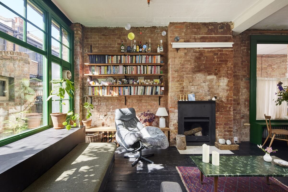 A Unique Home in a Former Furniture Workshop 2 living-room-brick-walls-bookshelves-fireplace-dark-wooden-floor-green-window-trims-nordroom