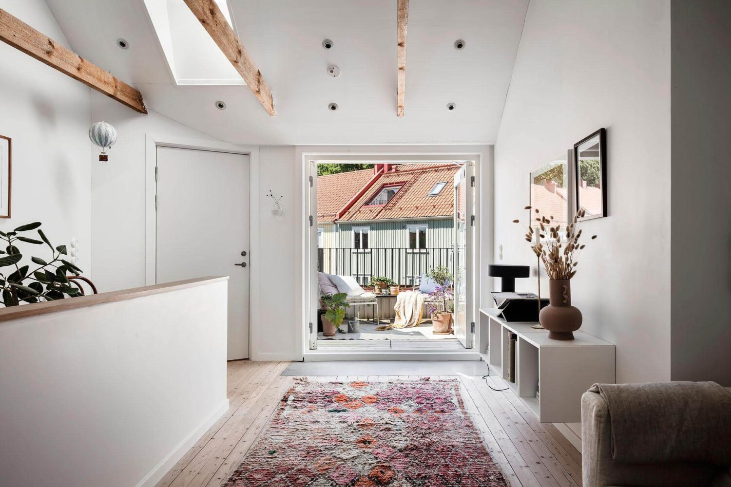 A Living Room with Pink Accents in a Light Attic Apartment 6 living-space-pink-rug-exposed-beams-roof-terrace-nordroom