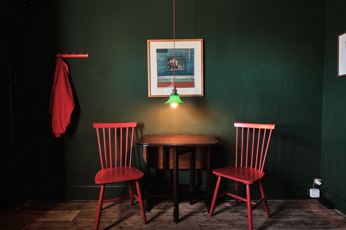 Bold Colors in a Charming English Cottage 5 moody-dark-green-sitting-room-red-chairs-nordroom