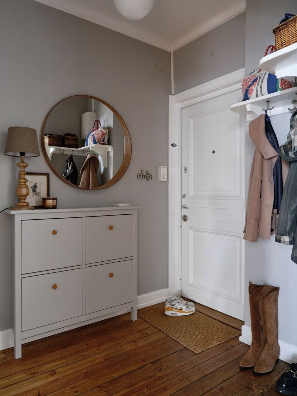 A Small Nordic Home with Dark Blue Accent Walls 18 hallway-light-gray-walls-shoe-cabinet-round-mirror-wooden-floor-nordroom