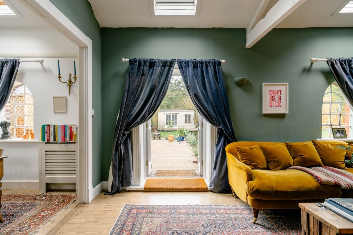 An English Barn Conversion Decorated in Green and Blue 4 sitting-room-blue-curtains-green-walls-ochre-yellow-sofa-skylights-nordroom