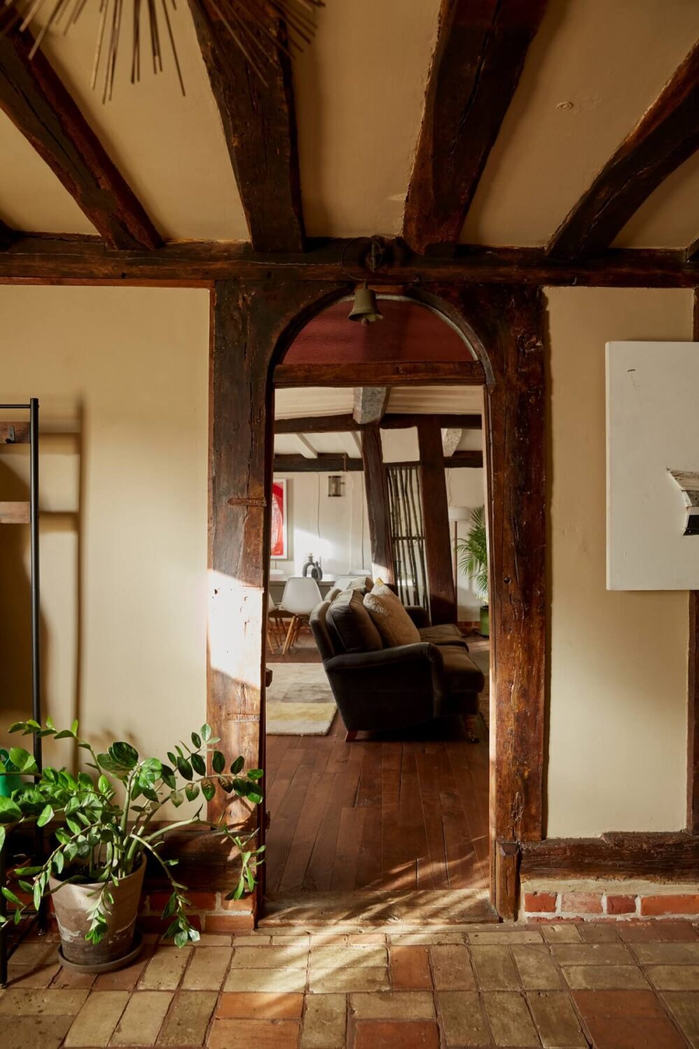 A Pink English Home That's Brimming with History 7 arched-wooden-doorway-living-room-hallway-stone-floor-exposed-beams-nordroom