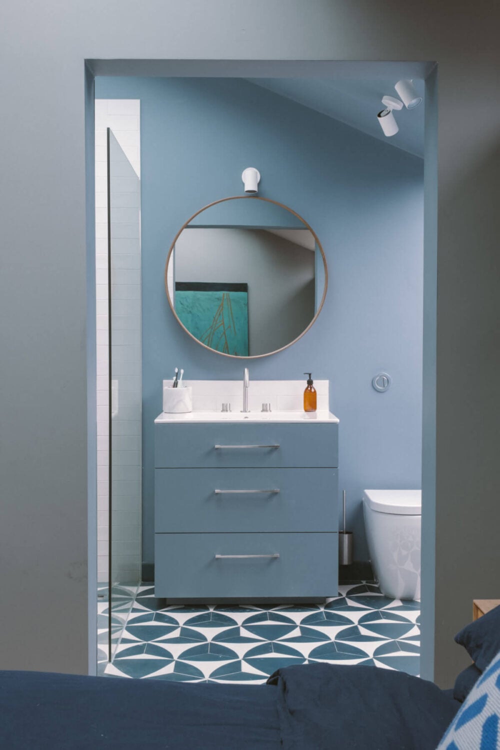 A Modern Split-Level Home with Colorful Rooms 24 blue-en-suite-bathroom-round-mirror-geometric-floor-tiles-nordroom