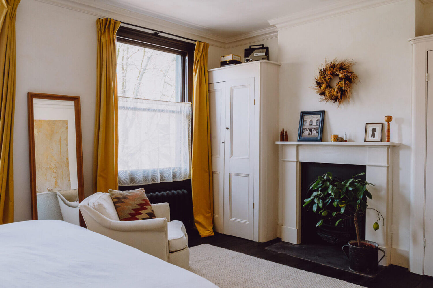 A Victorian Watch Shop is Now a Warm Sustainable Home 14 white-bedroom-ochre-yellow-curtains-fireplace-nordroom