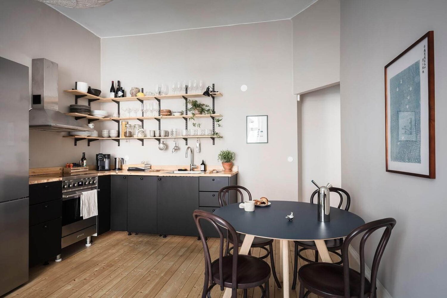 A Stylish Nordic Apartment with a Pink Bedroom 4 black-kitchen-open-shelves-round-dining-table-wooden-floor-nordroom