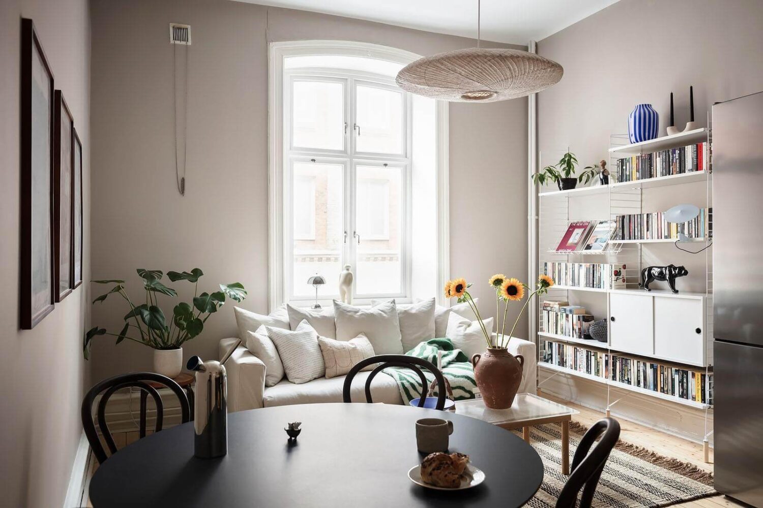 A Stylish Nordic Apartment with a Pink Bedroom 2 open-plan-living-room-round-dining-table-string-shelves-nordroom