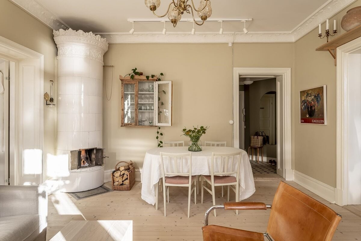 A Scandinavian Apartment with a Pale Yellow Kitchen 7 serene-living-room-dining-table-round-fireplace-nordroom