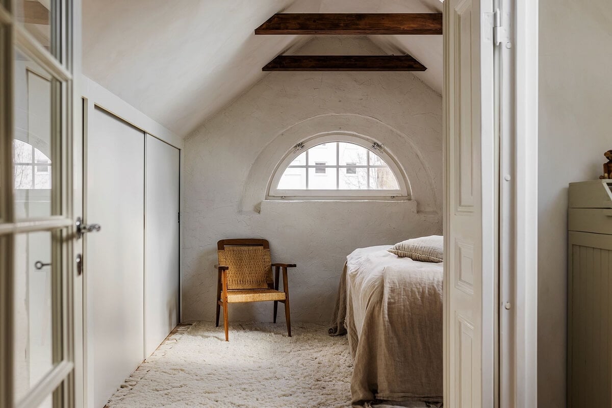 A Charming Attic Apartment with High Ceilings 16 attic-bedroom-slanted-ceiling-wooden-beams-arched-window-nordroom