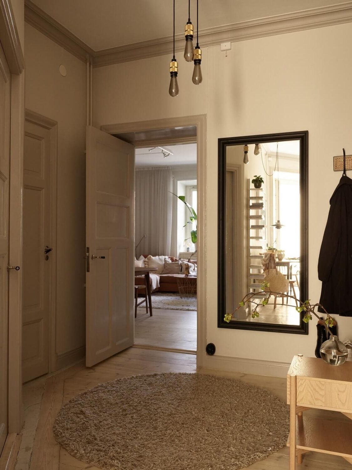 Warm Muted Colors in a Stockholm Apartment 17 hallway-round-jute-rug-large-mirror-beige-walls-nordroom