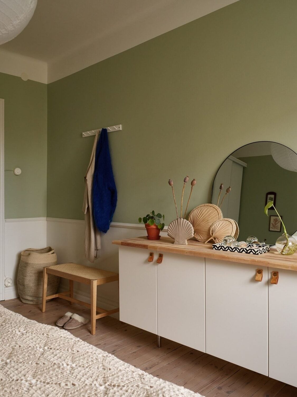 A Scandinavian Apartment with a Light Green Bedroom 17 light-green-walls-white-cabinets-wooden-top-round-mirror-bedroom-nordroom