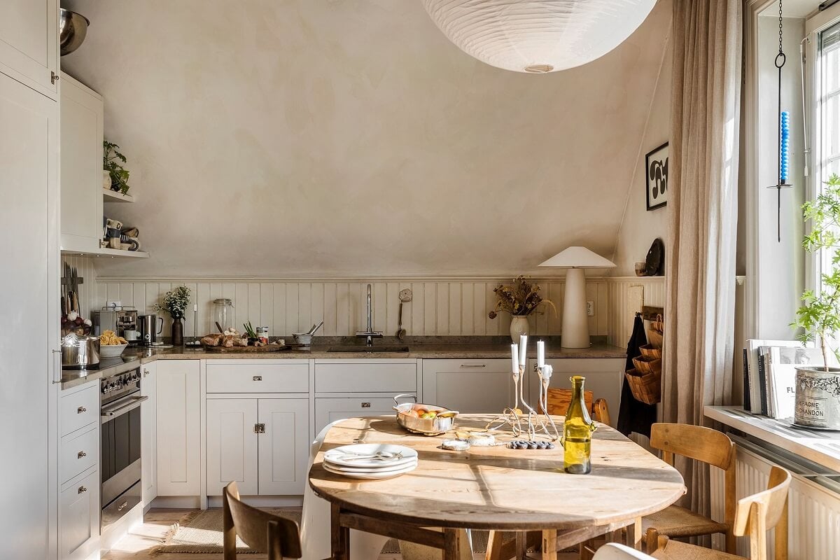 A Charming Attic Apartment with High Ceilings 3 light-kitchen-high-slanted-ceiling-round-dining-table-nordroom