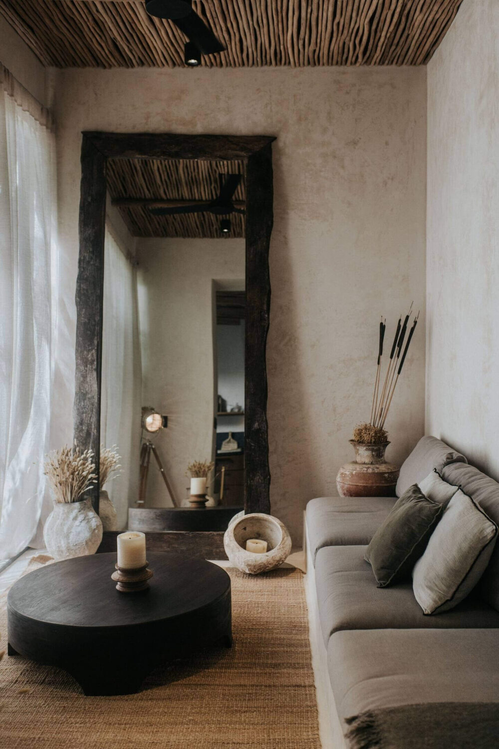 Rustic Wooden Elements in a Stylish Tulum Airbnb 8 small-sitting-room-gray-sofa-round-black-coffee-table-large-mirror-wooden-ceiling-nordroom