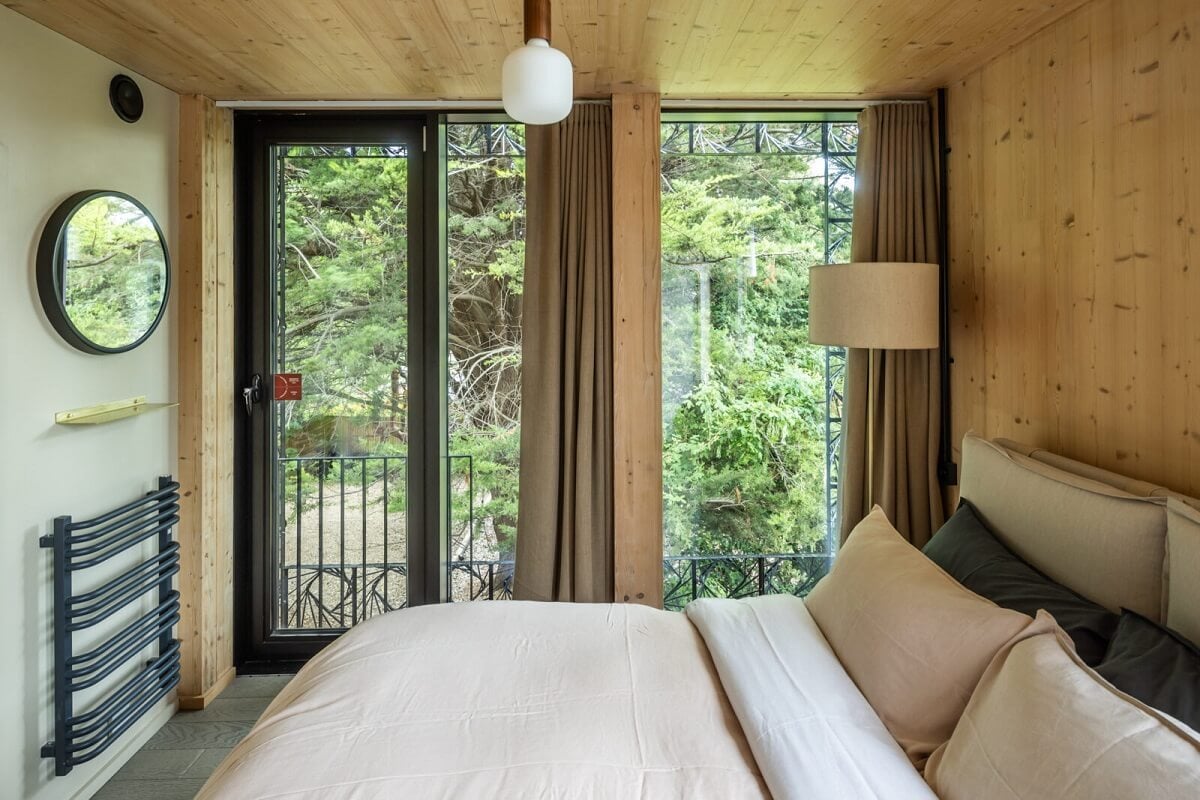 A Modern English Home with a Sculptural Facade 16 bedroom-wooden-walls-balcony-round-mirror-nordroom