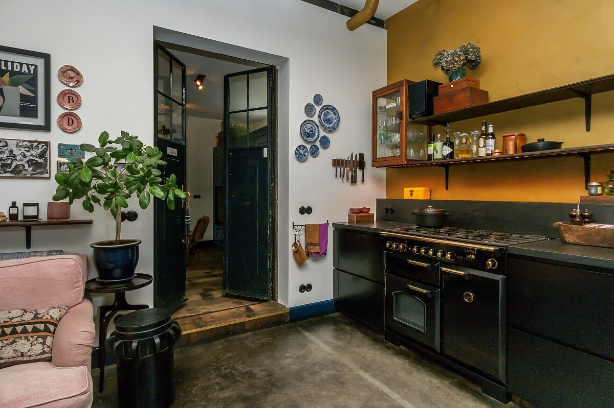 A Charming Colorful House in The Netherlands 3 mustard-yellow-accent-wall-black-kitchen-cabinets-open-shelves-nordroom
