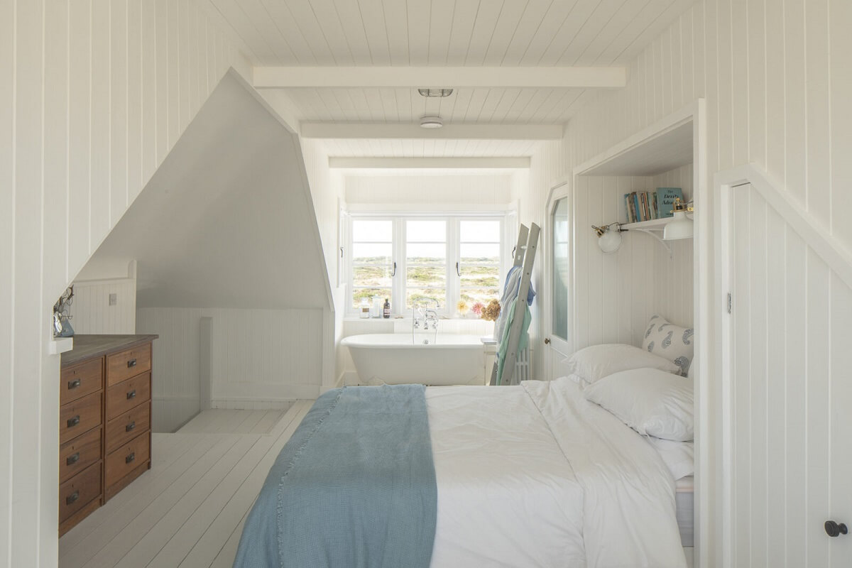 A Bright Coastal Home with Blue Color Accents in England 14 coastal-bedroom-slanted-ceiling-light-blue-throw