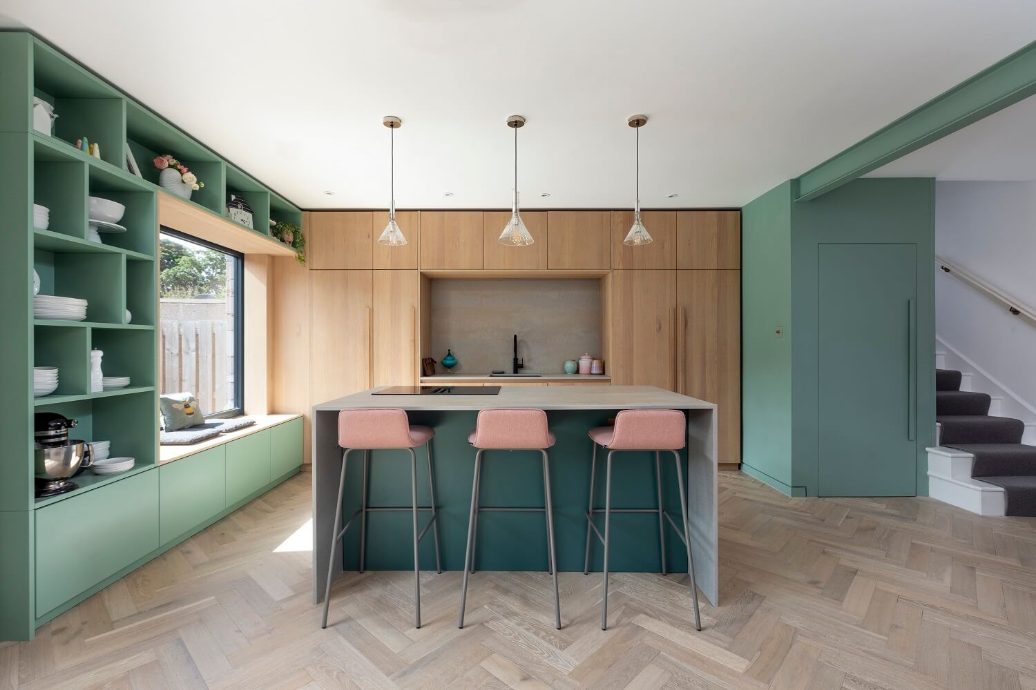 An Open-Plan Living and Kitchen in Green and Pink Tones 3 green-kitchen-island-open-cabinets-window-seat-agora-nordroom