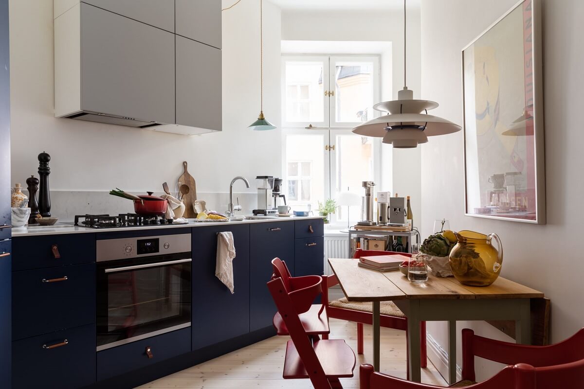 A Light Swedish Apartment with an Industrial Glass Wall 9 slanted-kitchen-with-table-blue-cupboards-nordroom