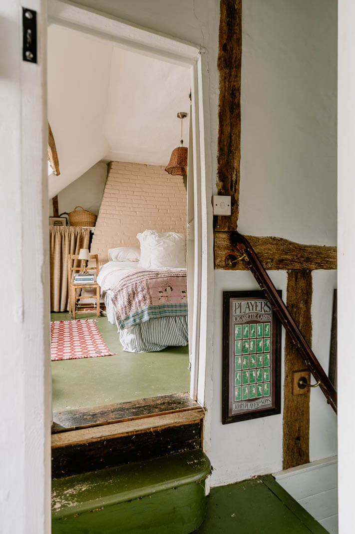 A Charming English Cottage with Color Accents 19 view-into-cottage-bedroom-slanted-ceiling-green-floor-nordroom