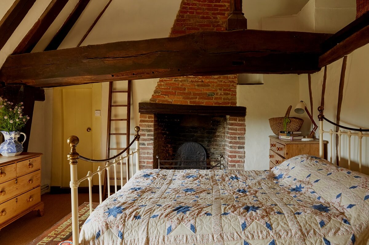 A Charming Historic Farmhouse with a Bright Yellow Kitchen 17 bedroom exposed beams brick fireplace