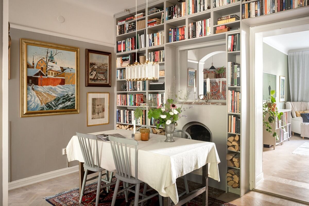 A Charming Open Plan Swedish Apartment 9 gray-dining-room-bookshelves-fireplace-nordroom