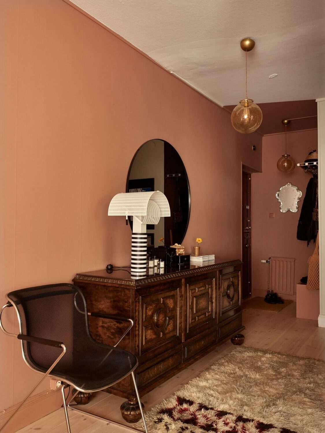 Warm Pink Tones in A Stockholm Apartment 13 hallway-pink-wall-antique-cabinet-round-mirror-nordroom