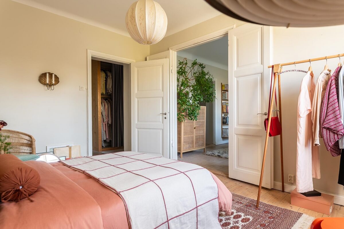 Colorful Decor in a Scandinavian Apartment 16 beige-bedroom-pink-bedding-clothing-rack-nordroom