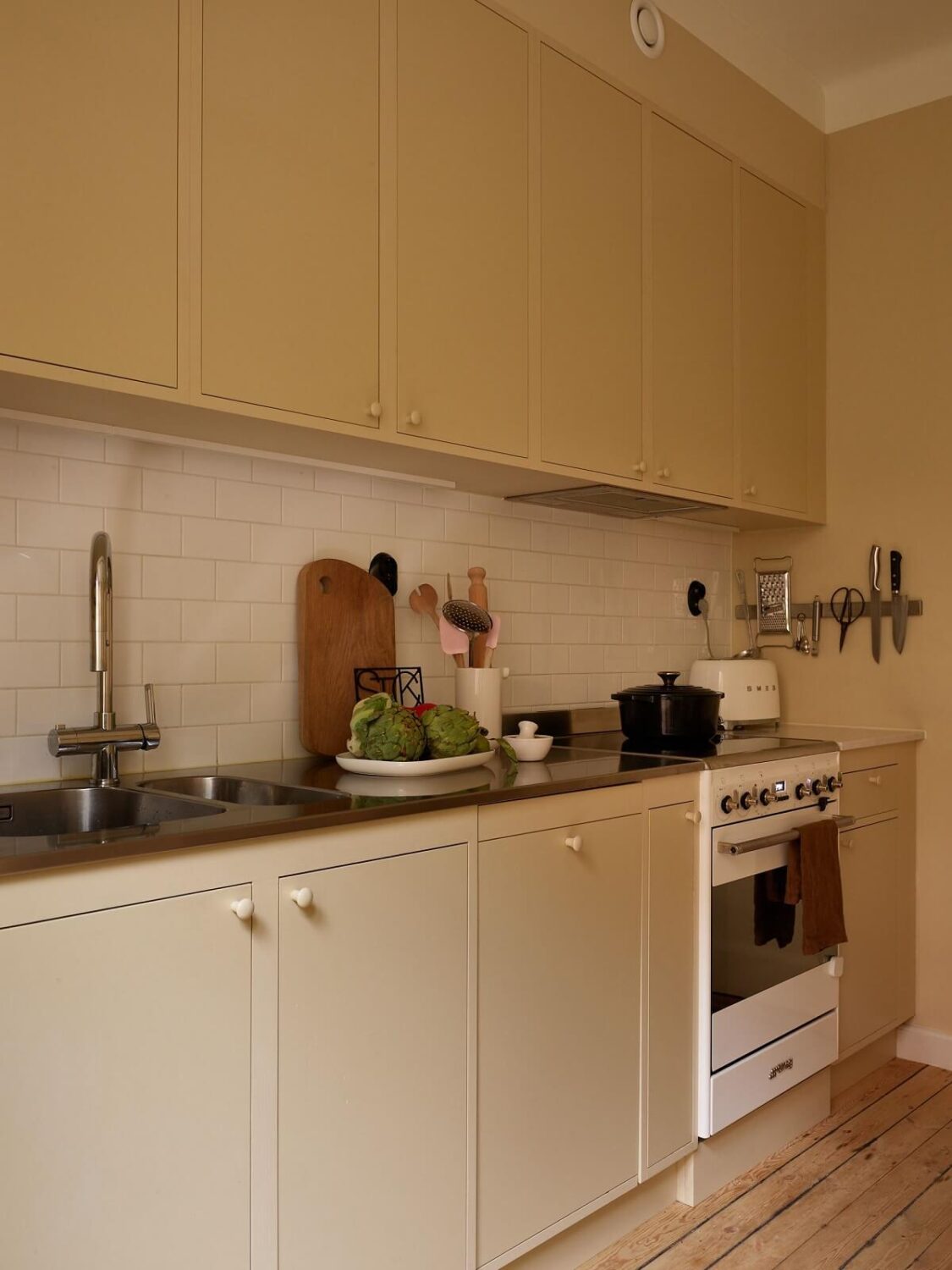 A Serene Light Colored Apartment with Bright Color Pops 3 beige kitchen cabinets