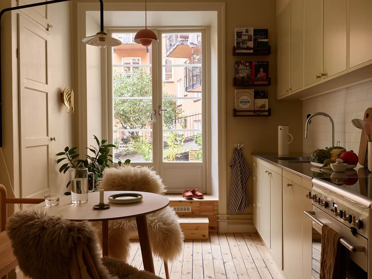 A Serene Light Colored Apartment with Bright Color Pops 1 beige kitchen wooden floor small round table nordroom