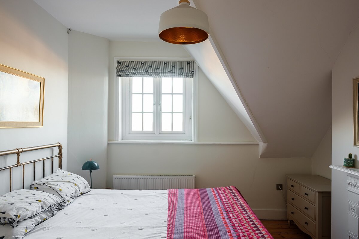 Playful Colors in a Historic Home in Kent 19 bedroom-slanted-ceiling-pink-bedspread