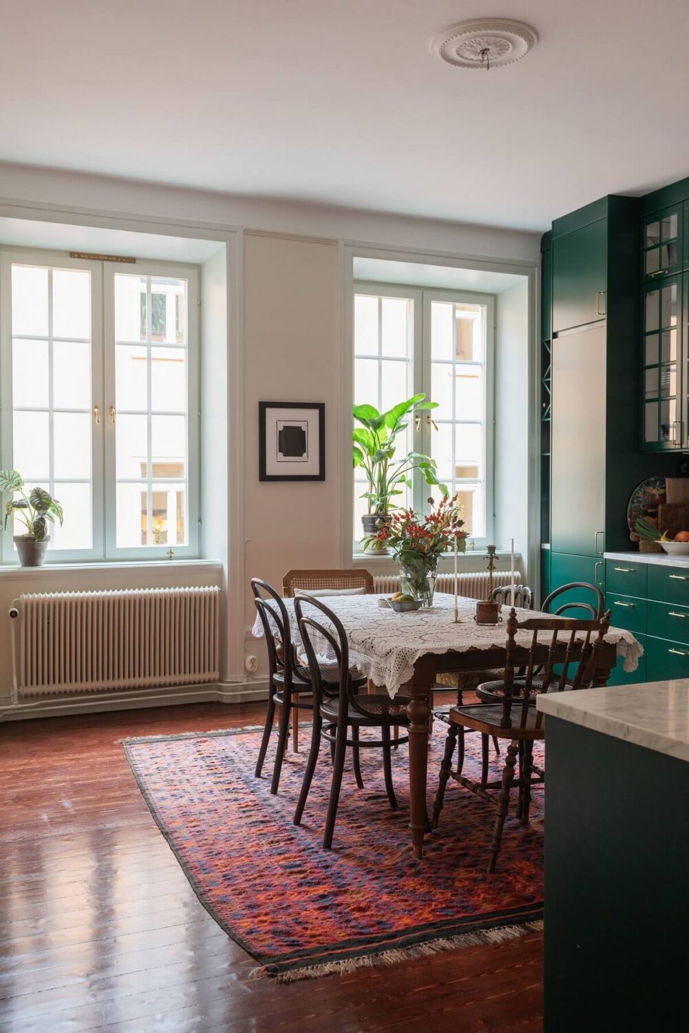 A Cozy Swedish Apartment with a Green Kitchen 11 big kitchen with green cabinets and dining table with rug nordroom