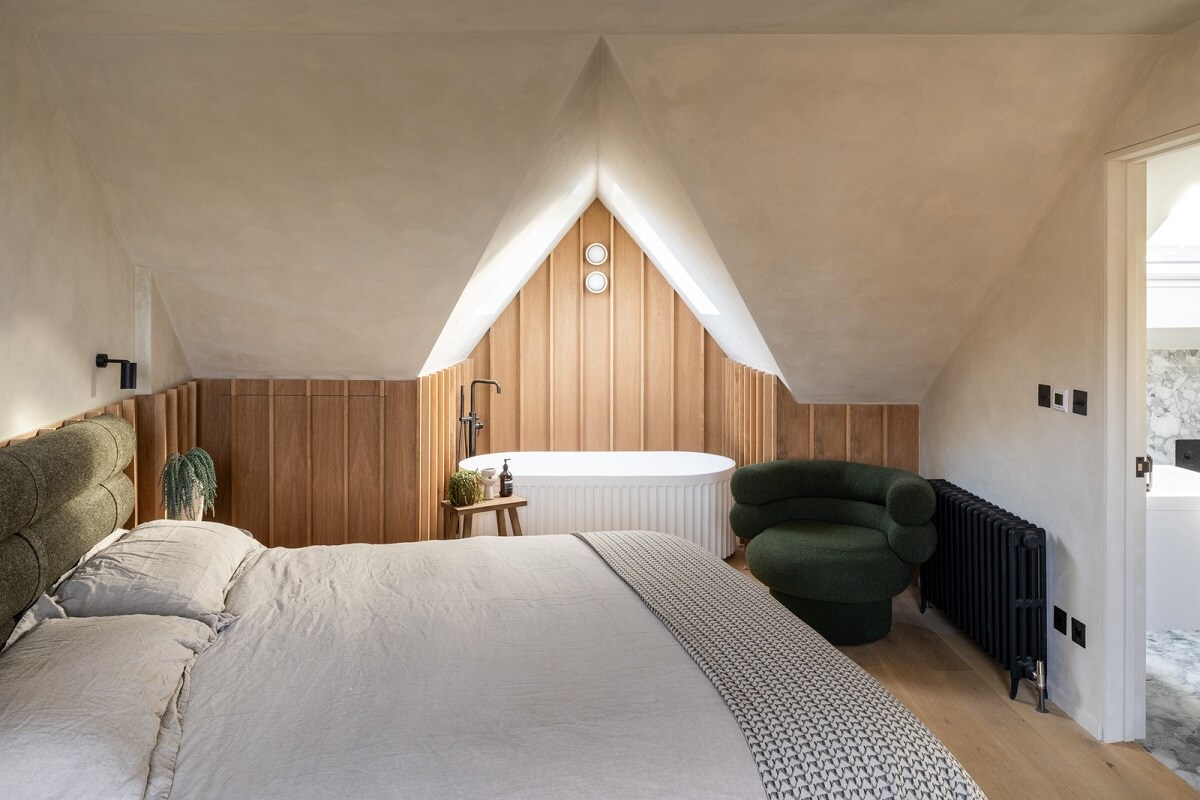 A Renovated Victorian House with Oak Features 17 attic bedroom with wooden accent wall and freestanding bath nordroom