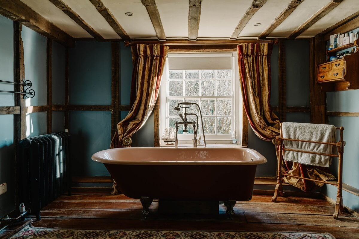A Cozy Historic English Country House with Exposed Beams 18 bathroom blue walls wooden beams freestanding bath historic english country house nordroom