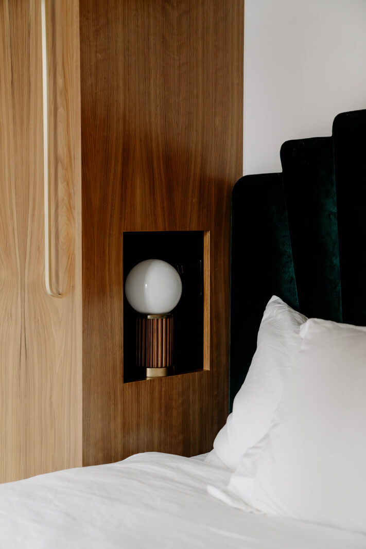 A Tiny London Apartment with Refined Materials and Colors 15 bed light fitted in walnut cabinets green velvet headboard nordroom
